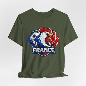 Może przedstawiać: Zielona koszulka z nadrukiem koguta, piłki nożnej i napisem "FRANCE". Kogut jest w kolorach francuskiej flagi: czerwonym, białym i niebieskim. Projekt znajduje się w tarczy.