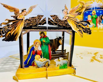 Può includere: Un biglietto di Natale pop-up 3D raffigurante la scena della Natività. Il biglietto presenta una stalla con Maria, Giuseppe e Gesù bambino, insieme ad angeli, una stella e animali. Il biglietto è fatto di carta e ha uno schema di colori giallo e marrone.