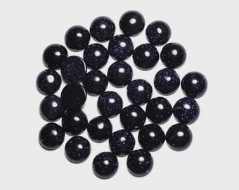 May include: A collection of dark blue, round gemstones with sparkling inclusions, resembling a starry night sky. These polished stones are scattered against a white background, showcasing their smooth, spherical shape. Ideal for jewelry making or crafts.