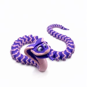May include: A purple and light pink articulated snake figurine with a cobra-style hood, large expressive eyes, and a forked tongue. The body features a repeating segmented pattern in purple with light pink accents along the edges and underside.