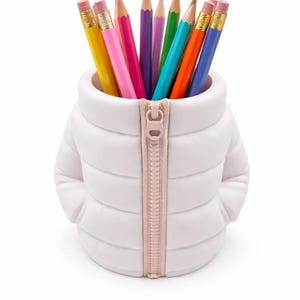 Peut inclure: Un pot à crayons blanc en forme de manteau d'hiver, avec une fermeture éclair rose clair. Le pot est rempli de crayons de couleur, dont des jaunes, roses, violets, verts, bleus et oranges.