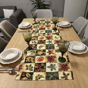 May include: A dining table set with a floral table runner featuring red, yellow, and green squares. The table is set with white plates, silverware, and green wine glasses. The room has gray walls and chairs. The table runner is approximately 150 cm long.