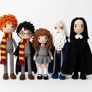 May include: Five crocheted dolls of characters from a fantasy series. The dolls have yarn hair, detailed clothing, and accessories. The characters include a boy with glasses, a girl, and a wizard with a long white beard. The dolls are standing on a white surface.