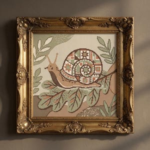 May include: Framed cross-stitch art featuring a snail with a patterned shell, resting on leaves. The artwork uses shades of brown, green, and beige. The ornate gold frame adds a classic touch to the nature-themed piece.