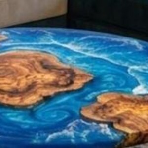 May include: Round wooden table with a blue epoxy resin design resembling ocean waves. The table features natural wood grain patterns and measures approximately 36 inches in diameter.