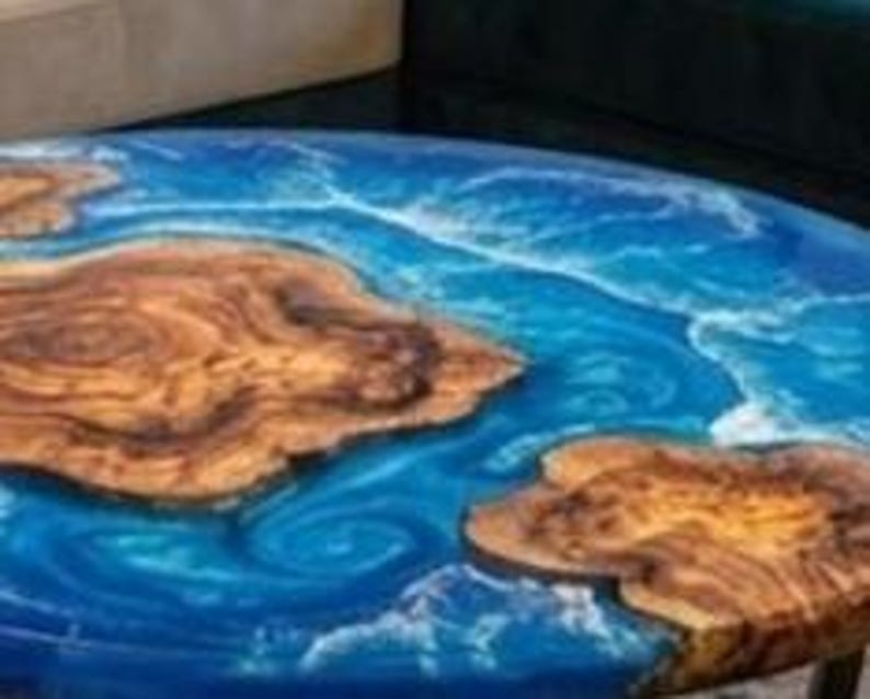 May include: Round wooden table with a blue epoxy resin design resembling ocean waves. The table features natural wood grain patterns and measures approximately 36 inches in diameter.
