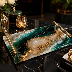 May include: Rectangular decorative tray with gold handles. The tray features a marbled design with shades of green, white, and gold. The tray is on a black marble surface.