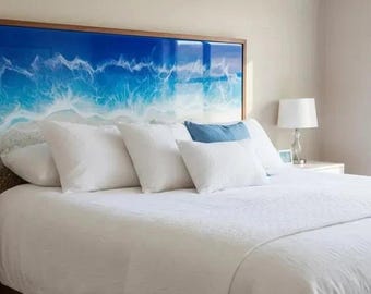 May include: A bedroom scene featuring a bed with a white comforter and pillows. A large headboard with a blue and white ocean wave design is mounted above the bed. A bedside table with a lamp is visible.