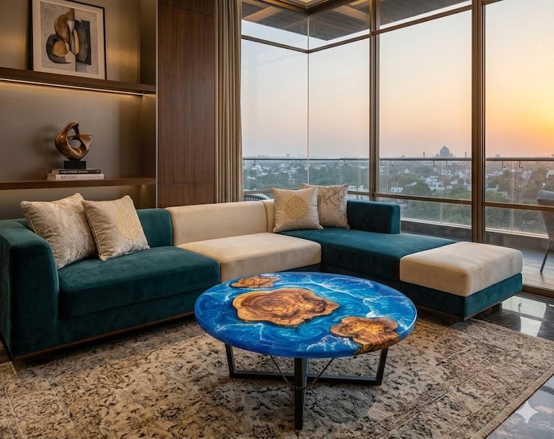 May include: A modern living room with a teal sectional sofa, beige cushions, and a round coffee table. The coffee table has a blue epoxy resin top with wooden accents. The room has large windows with a view of a cityscape.