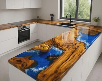 May include: A modern kitchen with white cabinets and a unique countertop. The countertop features a wood grain design with a blue epoxy resin river. A bowl of lemons sits on the countertop.