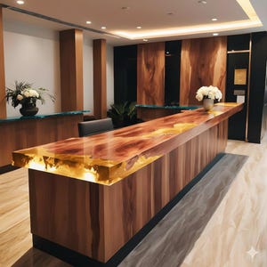 Può includere: Un moderno bancone di ricevimento in legno con un piano in legno a bordo vivo racchiuso in resina trasparente. Il bancone ha una calda venatura naturale del legno ed è illuminato da un bagliore dorato. Il fronte è composto da pannelli verticali in legno.
