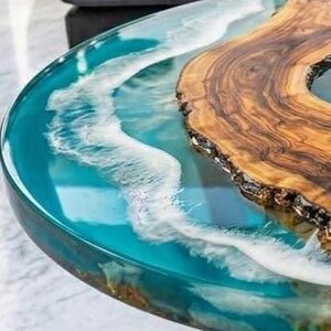 May include: A unique, handcrafted coffee table with a wood slab and epoxy resin design. The table features a natural wood grain section and a turquoise resin river, creating a wave-like effect. The table's dimensions are not visible in the image.