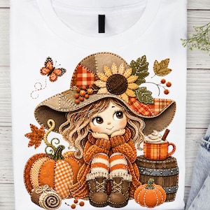 May include: A white t-shirt featuring a graphic illustration of a character with long hair wearing a wide-brimmed hat decorated with a sunflower and plaid patterns. The character sits near a pumpkin, a barrel with a mug, and a butterfly.