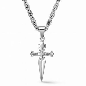 May include: A silver-colored pendant necklace featuring a cross design with a dagger-like point. The cross has a detailed, layered appearance. The chain is a thick, twisted rope style. The jewelry is displayed against a white background.