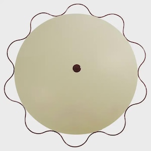May include: A circular table with a smooth, light beige top and a dark maroon, wavy metal frame edge. The center of the table features a small, dark maroon circular accent piece. The design is simple, featuring a flat surface and a scalloped border.