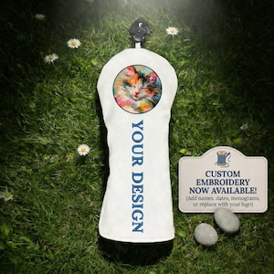 Könnte beinhalten: Ein weißer Golfschlägerhaube mit einem runden Aufnäher, der eine farbenfrohe, malerische Illustration einer Katze zeigt. Der Text YOUR DESIGN ist vertikal in Blau aufgedruckt. Ein rechteckiges Schild daneben zeigt CUSTOM EMBROIDERY NOW AVAILABLE!