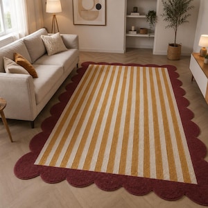 May include: A rectangular area rug featuring a central pattern of vertical mustard yellow and cream stripes. The rug is framed by a wide, solid deep burgundy border with a distinct scalloped edge that follows the entire perimeter of the piece.