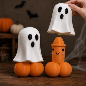 May include: Three decorative figurines featuring two white ghosts with black eyes and mouths, and one orange phallic-shaped character with a smiling face and pink cheeks. The figures are constructed from a textured material with visible layers.