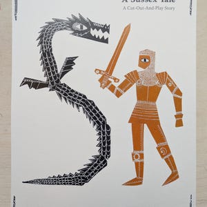 May include: A paper craft kit titled "The Golden Knight, A Sussex Tale." The illustration shows a black dragon and an orange knight with a sword. The kit includes a story and figures to cut out and play with.