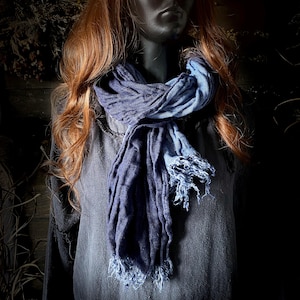 Peut inclure: Écharpe bleue à deux tons avec une bordure effilochée. L'écharpe est drapée autour du cou d'un mannequin, mettant en valeur sa texture et ses variations de couleur. L'écharpe semble être faite d'un tissu doux et léger.