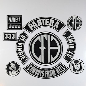 May include: A collection of black and white patches featuring the band name "Pantera" and related imagery. Includes patches with text, logos, and illustrations, suitable for jackets or bags.