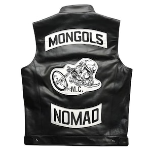 Pode incluir: Um colete de couro preto com três emblemas brancos nas costas. O emblema superior diz MONGOLS em texto preto. O emblema central retrata um personagem de desenho animado em uma motocicleta com o texto M.C. abaixo. O emblema inferior diz NOMAD.