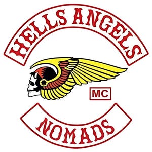 May include: A graphic patch featuring the text HELLS ANGELS in a red arched banner above a central emblem of a winged skull with yellow and red feathers. Below the emblem is a red box with MC and a second red arched banner with the text NOMADS.