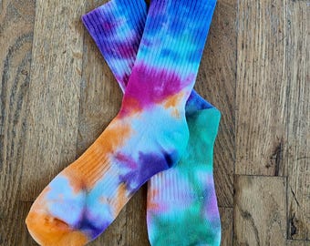 Peut inclure: Deux paires de chaussettes de sport avec un motif tie-dye vibrant. Les chaussettes présentent un mélange de couleurs, notamment orange, violet, rose, bleu et vert. Les chaussettes sont faites d'une matière douce et conviennent à un usage quotidien.