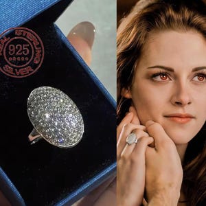 Puede incluir: Un anillo de plata con una cara ovalada cubierta de pequeñas piedras brillantes. El anillo se muestra en una caja de joyería azul. El anillo está marcado "REAL STERLING 925 SILVER".