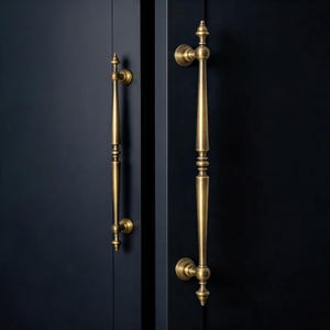 Puede incluir: Dos tiradores de puerta de latón antiguo con detalles ornamentados están montados en una puerta azul oscuro. Los tiradores tienen un diseño vertical con elementos decorativos y una estética clásica y vintage. Los tiradores miden unos 30 cm de largo.