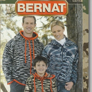 May include: A magazine cover featuring a family wearing camouflage-patterned sweaters. The magazine is titled "Urban Camouflage" with the tagline "Learn to knit and crochet instructions included".