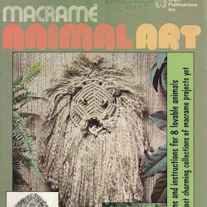 May include: A book cover with the title "Macrame Animal Art" in orange and brown letters. The cover features a macrame lion with a brown background and green ferns on the sides. The book is by Susan Shwartz and is a collection of 8 macrame animal projects.