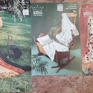May include: Three crochet pattern books from King Patterns. The first book features a brown and orange crochet blanket with fringe. The second book features a white crochet baby blanket in a rocking chair. The third book features a white and brown crochet square blanket with fringe.