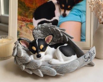 May include: A figurine of a sleeping black and white dog resting inside a pair of grey sculpted angel wings. The dog has tan markings above its eyes and pink inner ears. The name Sniffet is inscribed in black cursive script on the right wing.