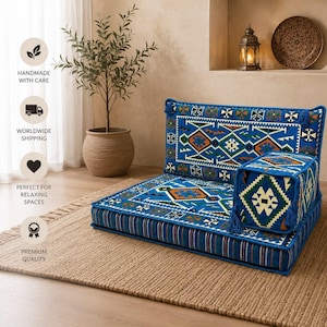 May include: A floor sofa set featuring a rectangular base cushion and a backrest cushion with a matching armrest. The fabric is vibrant blue with intricate geometric patterns in white, orange, green, and black. The base has a striped side border.