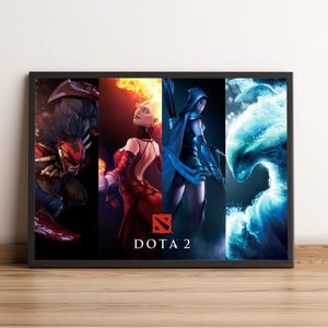 May include: A framed poster featuring four characters from the video game Dota 2. The characters are depicted in vibrant colors, with the Dota 2 logo and text at the bottom. The poster is set against a neutral background.