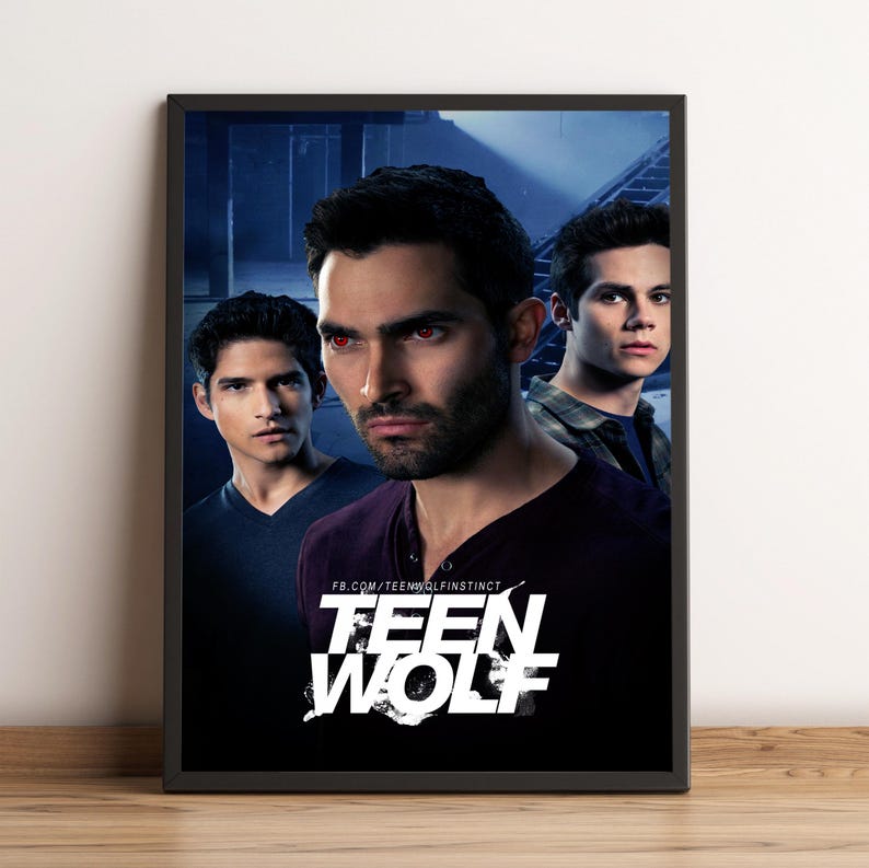 May include: A framed poster featuring three men from the TV show "Teen Wolf." The central figure has red eyes and a serious expression. The poster has the show's title in white block letters and a dark background.