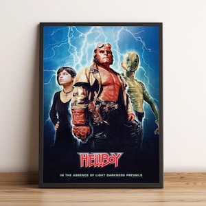 May include: A framed movie poster for "Hellboy" featuring three characters against a blue background with lightning. The title is in red, and the tagline reads "In the absence of light darkness prevails."