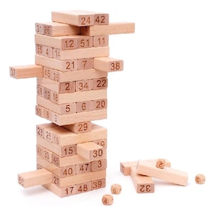 May include: A wooden block stacking game with numbered blocks. The tower is partially constructed, with some blocks removed and scattered nearby. The blocks are light brown, and the numbers are printed in black.