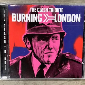 May include: A CD case featuring the album "Burning London" by The Clash Tribute. The cover art depicts a pink and black image of a police officer against a red and blue background. The album title is in white.