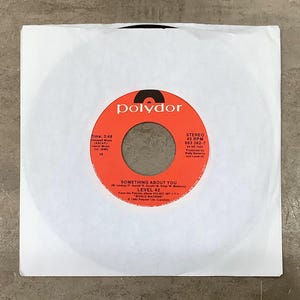 May include: A 45 RPM vinyl record in a white paper sleeve. The orange centre label features the Polydor logo, the song title Something About You by Level 42, the album World Machine, and technical details including the 3:48 time and 883 362-7 code.