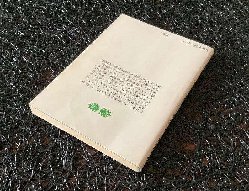May include: The back cover of a book with a white background and black text. The text describes a story about a boy who can see the mythical creatures called "コロポックル".