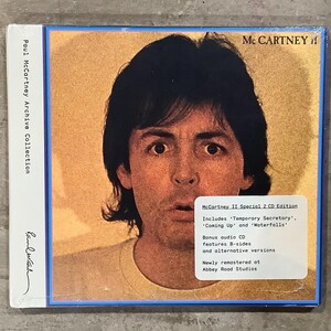 May include: A Paul McCartney II Special 2 CD Edition music album featuring a portrait of Paul McCartney on the cover. The text reads McCartney II, Paul McCartney Archive Collection, and includes details about bonus audio CDs and Abbey Road Studios.