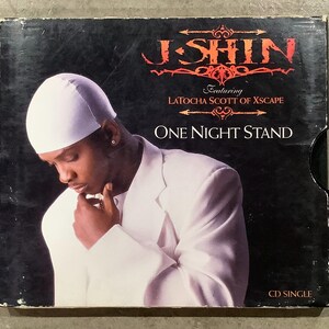 May include: CD single case featuring J Shin, with the text "One Night Stand" and "Featuring Latocha Scott of Xscape." The cover art shows a person in a white suit and cap against a black background.