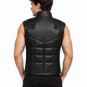 Könnte beinhalten: Eine schwarze Lederweste mit Stehkragen, gestepptem Paneeldesign am unteren Rücken und strukturierten Schulterdetails. Das ärmellose Kleidungsstück ist aus glatten Lederbahnen gefertigt und bietet eine körpernahe Passform.