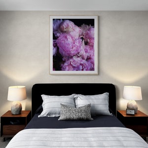 Puede incluir: Un dormitorio con una cabecera negra y una colcha azul marino con rayas blancas. Dos mesitas de noche con l&aacute;mparas y una impresi&oacute;n enmarcada de peon&iacute;as rosas en la pared.