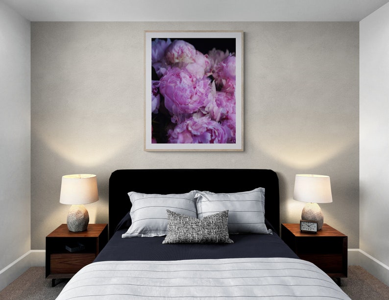Puede incluir: Un dormitorio con una cabecera negra y una colcha azul marino con rayas blancas. Dos mesitas de noche con l&aacute;mparas y una impresi&oacute;n enmarcada de peon&iacute;as rosas en la pared.