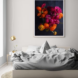 May include: A framed print of a bouquet of orange, pink, and red ranunculus flowers against a dark blue background.