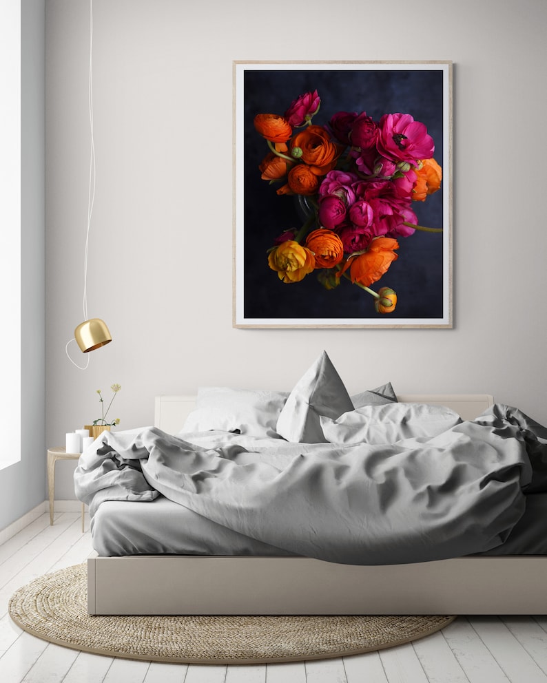 May include: A framed print of a bouquet of orange, pink, and red ranunculus flowers against a dark blue background.