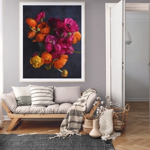 May include: A framed photograph of a bouquet of orange and pink ranunculus flowers against a dark blue background.